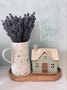 a ceramic house next to a vase with lavender in it and a sign that says home sweet home