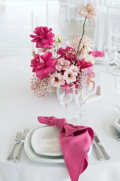 the table is set with pink and white flowers, silverware, and napkins