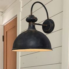 an old fashioned wall light hanging on the side of a house with white sidings