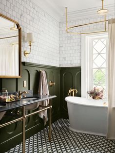 a bathroom with green walls, black and white tile flooring and a gold framed mirror on the wall