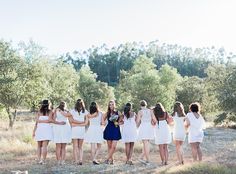 a group of women in white dresses standing next to each other on a dirt road