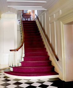 a staircase with red carpet and white walls