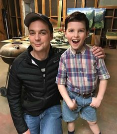 two young men posing for a photo in front of an art studio with their arms around each other