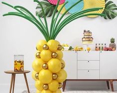 a large pineapple balloon sitting on top of a table next to a vase filled with flowers