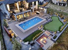 an aerial view of a house with a swimming pool in the yard and landscaping around it