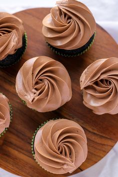 chocolate cupcakes with frosting on a wooden plate