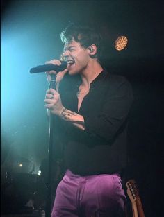 a young man singing into a microphone on stage