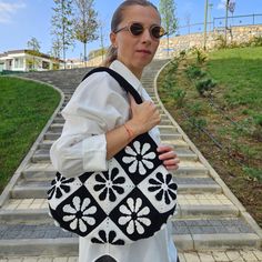 a woman carrying a black and white handbag on top of a set of steps