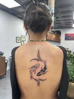 a woman with a tattoo on her back is looking at the fish in the water