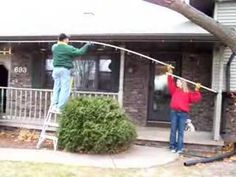 two people are hanging clothes on a line outside the house and one person is standing on a ladder