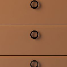 three drawers with black handles and rings on the bottom one drawer is brown, while the other two are tan