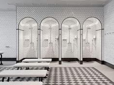 a white tiled bathroom with benches and mirrors