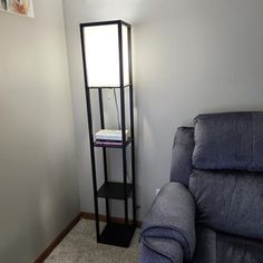 a living room with a blue couch next to a book shelf on the wall and a window