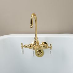 a gold faucet on the side of a white bathtub