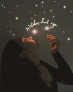 a woman holding a lite up sparkler in front of her face with words written on it