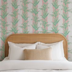 a bed with two pillows on top of it in front of a wallpapered headboard