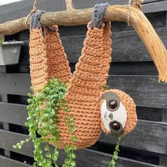 two slots hanging from a tree branch in front of a wooden fence with green plants