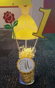 a vase filled with yellow flowers sitting on top of a carpeted floor next to a number one sign