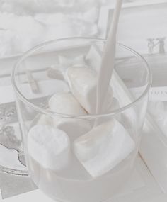 a glass filled with marshmallows on top of a table