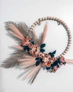 a necklace with flowers, feathers and beads hanging from it's centerpiece on a white background