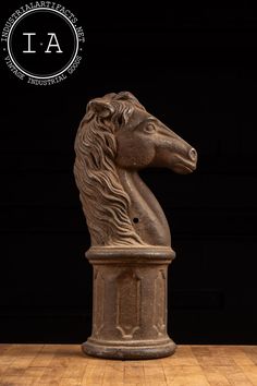 a statue of a horse head on top of a wooden table next to a black wall