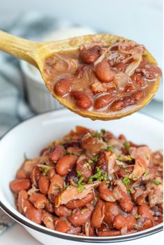 a spoon full of beans and meat in a bowl