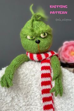 a green stuffed animal wearing a red and white striped scarf