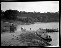 an old black and white photo of people on the side of a road next to water