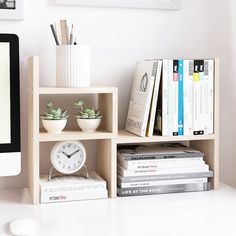 a book shelf with books, plants and a clock on it's side next to a stack of books