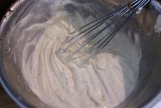 a metal bowl filled with cream and whisk