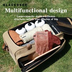 an open suitcase on the grass with several items in it, including gloves and other things