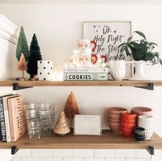 a shelf filled with christmas decorations and books on top of a kitchen counter next to candles