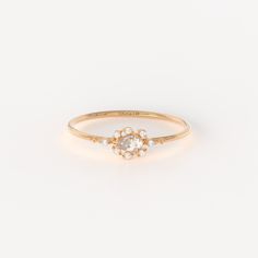 a gold ring with an oval shaped diamond and small white stones on the side, set in