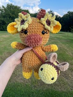 a hand holding a small stuffed animal in the grass