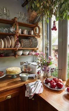 a wooden table topped with lots of plates and bowls filled with food next to a window