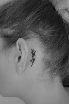 a woman with a small rose tattoo on her left behind the ear, looking down