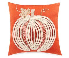 an orange and white pillow with a decorative pumpkin design on the front, sitting on a white background