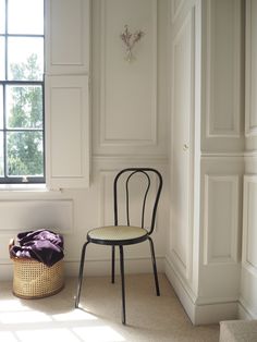 a chair sitting in front of a window next to a small basket on the floor