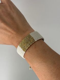 Embrace the fusion of simplicity and modern elegance with our handwoven cream and gold bracelet. Expertly crafted, this piece features a wide band of durable cream-colored threads, elegantly complemented by a central stripe of gold that catches the light with every movement. Its adjustable design ensures a perfect fit for any wrist size, making it an ideal choice for both everyday wear and special occasions. Celebrate the beauty of artisanal craftsmanship and sustainable fashion with this unique White Bohemian Braided Bracelets For Everyday, Gold Woven Braided Bracelets For Friendship, Adjustable Woven Gold Jewelry, Adjustable Woven Jewelry For Everyday Wear, Adjustable Woven Jewelry For Everyday, White Bohemian Woven Jewelry, Bohemian White Woven Jewelry, Gold Woven Bracelets For Friendship, Handmade White Braided Bracelets For Everyday