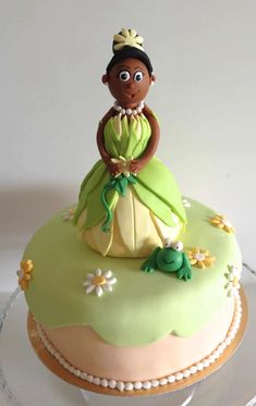 there is a cake decorated with a princess and frog on the top of it's stand