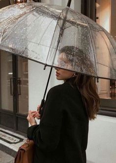 a woman walking down the street while holding an umbrella over her head with water droplets on it