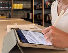 a woman is holding a pen and writing on an ipad