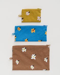 three zippered pouchs with flowers on them, one in blue and the other in brown