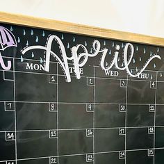 a chalkboard calendar with the word april written on it and an umbrella drawn on it