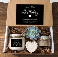 a birthday gift box with candles, cookies and a succulent plant in it