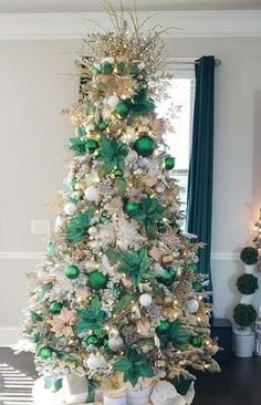 a white christmas tree with green and gold ornaments