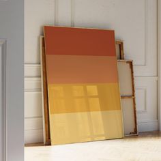 an orange and yellow painting sitting on top of a hard wood floor next to a white door