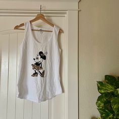 a white tank top with a minnie mouse on it hanging from a hanger in front of a door