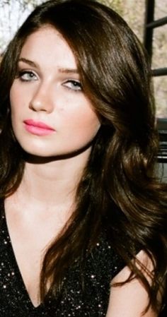 a woman with long brown hair wearing a black dress and pink lipstick on her lips