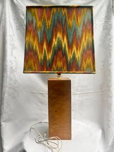 a lamp that is on top of a wooden block with a fabric shade over it